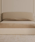 Beige bed with matching nightstands in a minimalistic bedroom setting.